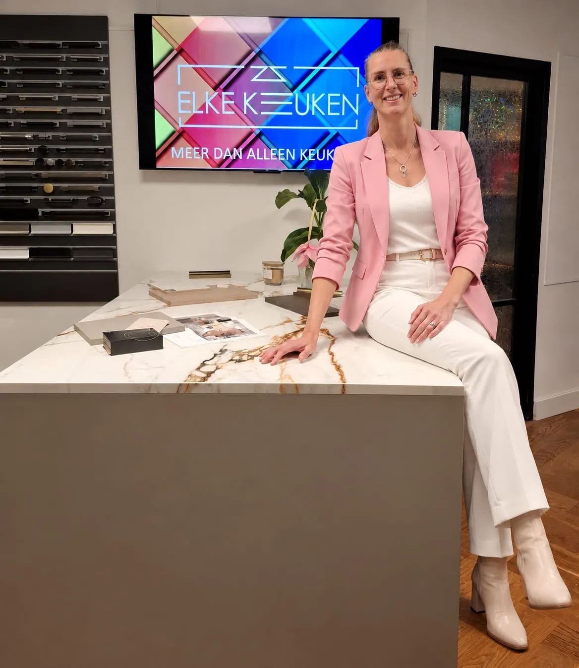 Ellis Keklikci–van Rooijen in de showroom van Elke Keuken, bij het logoscherm 'Elke Keuken · meer dan alleen keukens'.