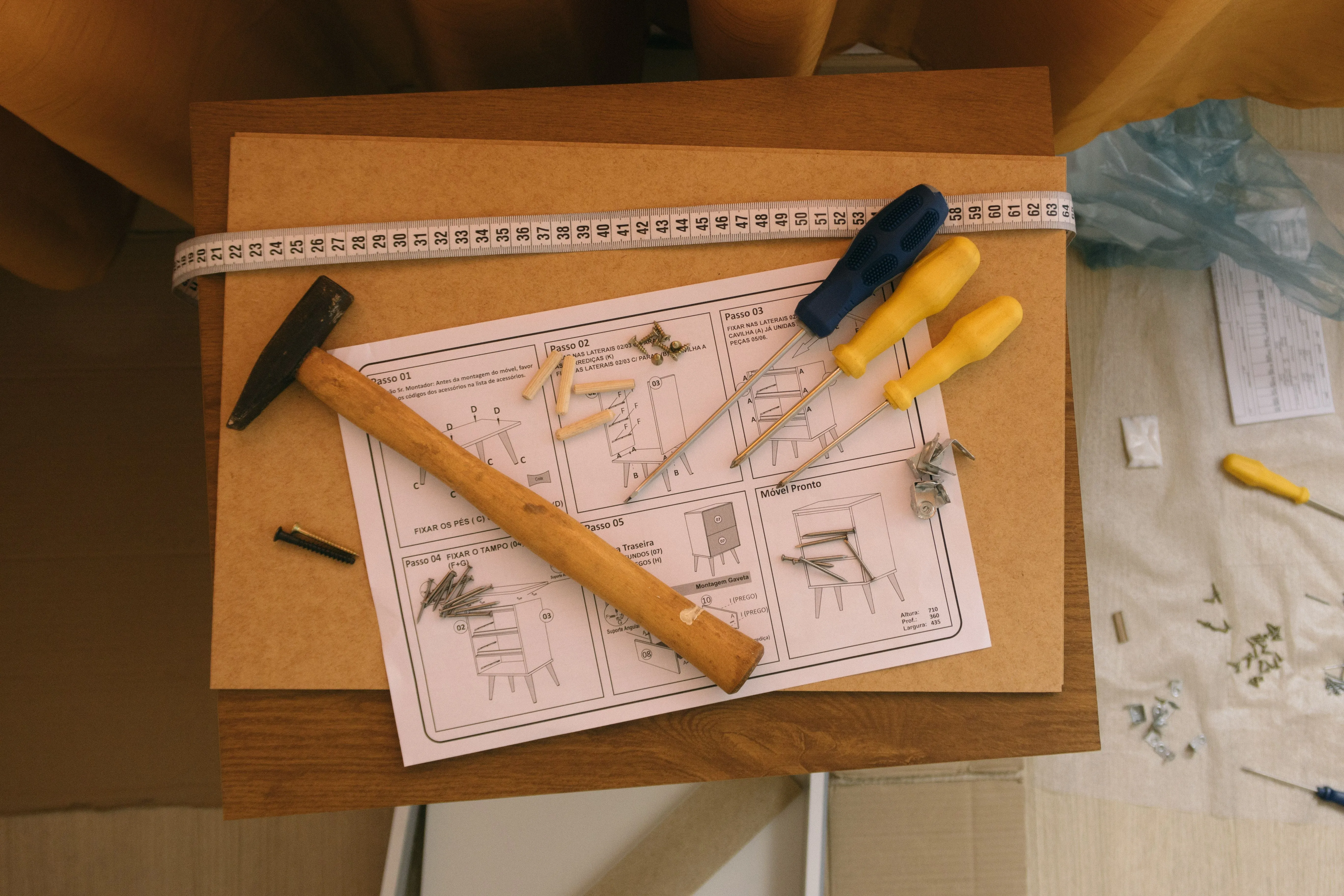 Werkbank met bouwtekening, potloden en rolmaat tijdens de voorbereiding van een keuken-installatie.
